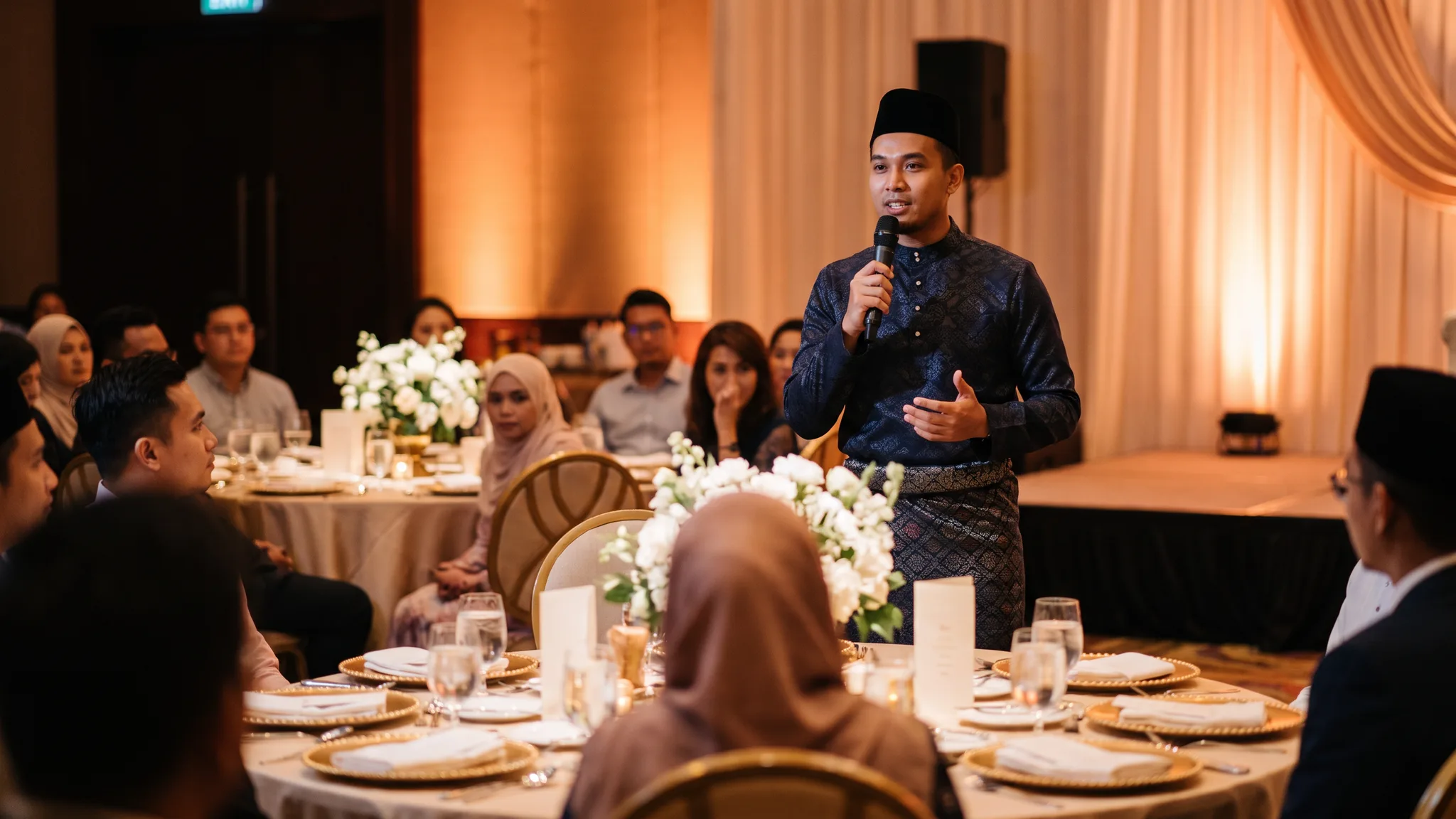 Juruacara majlis lelaki Malaysia memegang mikrofon di majlis perkahwinan