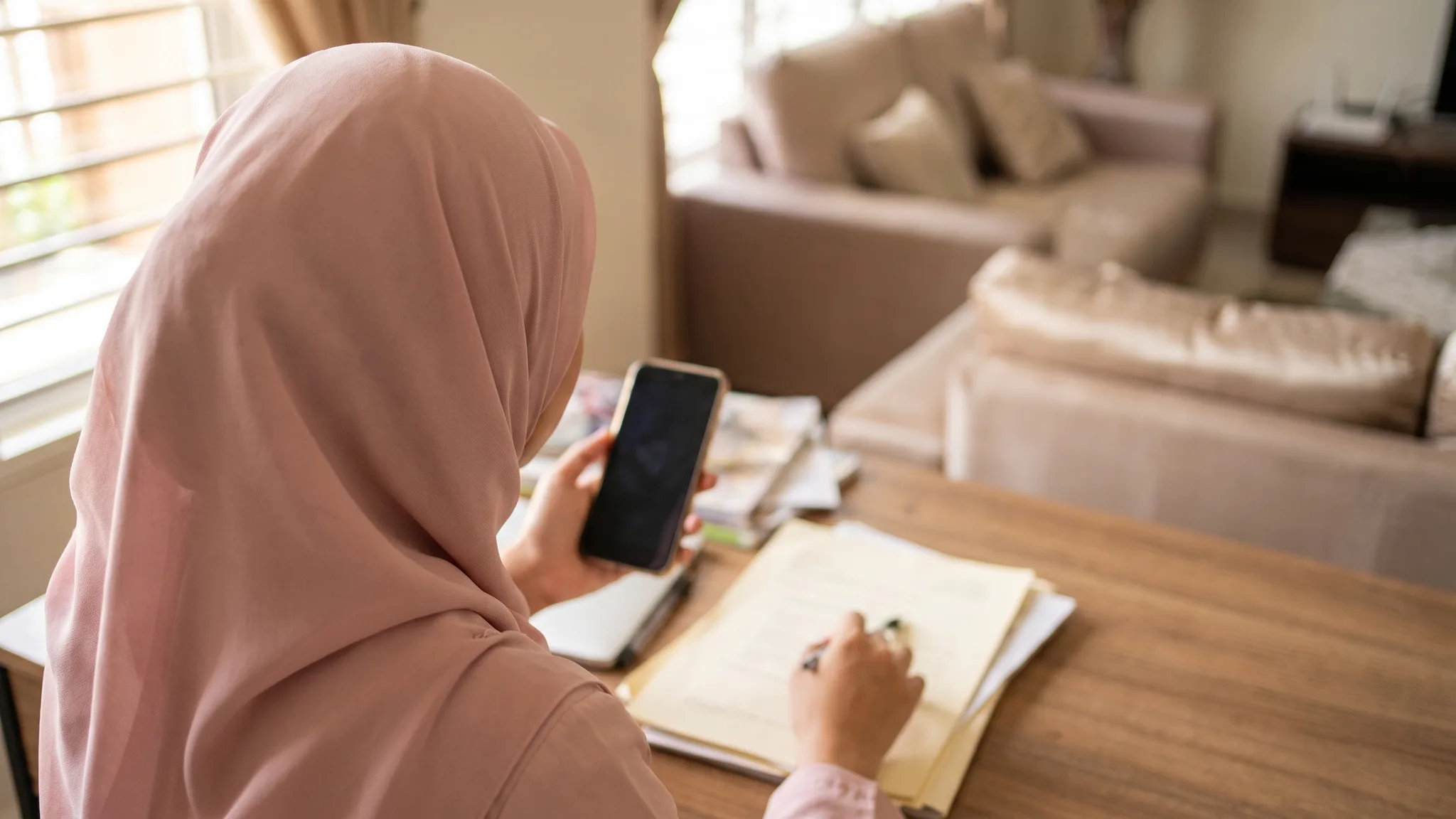Wanita Malaysia menguruskan dokumen rasmi dan panggilan telefon di rumah